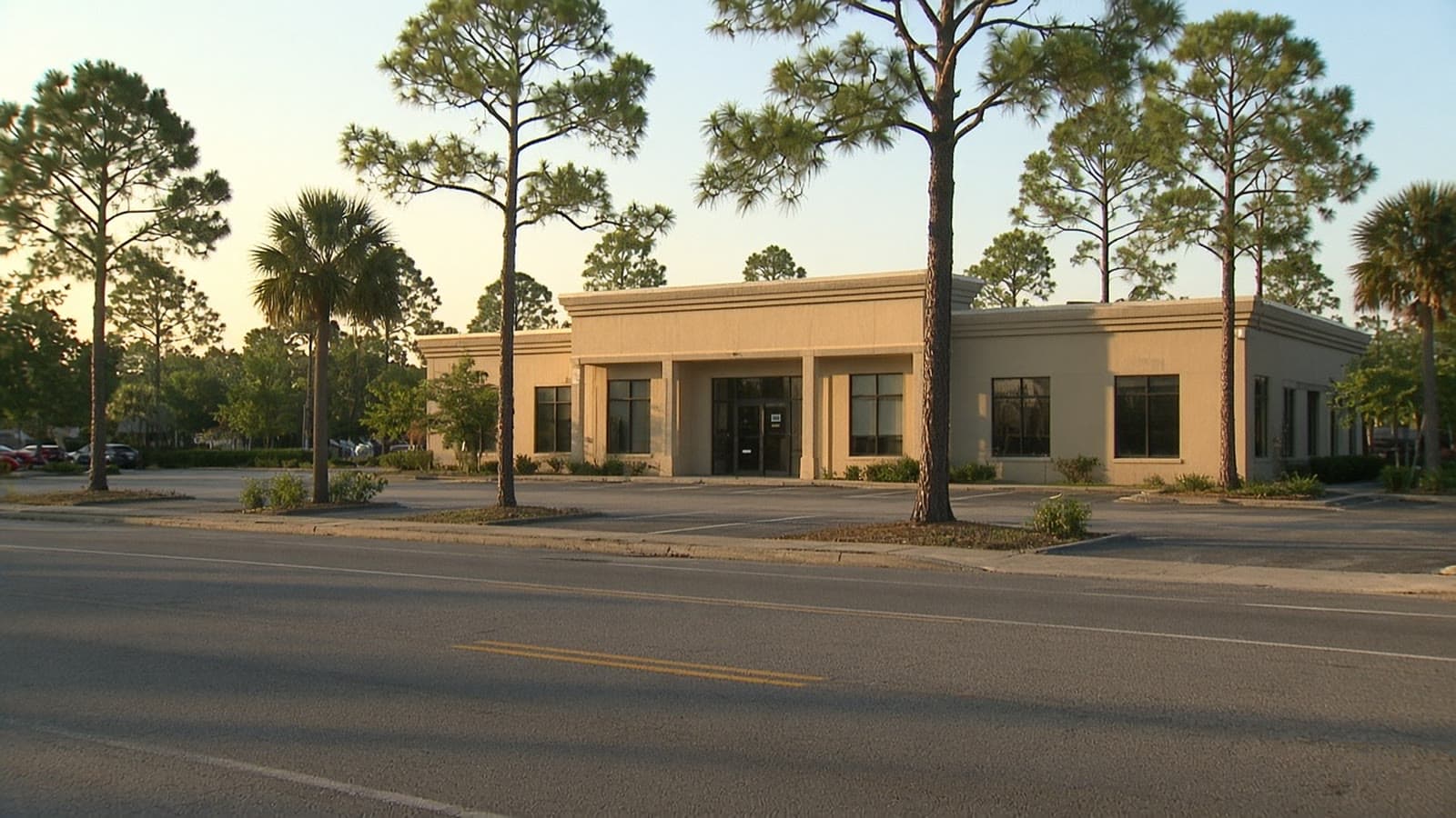 Late-afternoon view across a Spring Hill road toward a single-story office and its parking lot